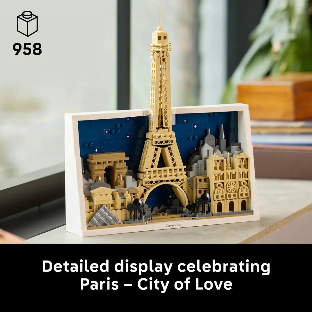 LEGO Paris skyline model featuring the Eiffel Tower and Louvre displayed on a wooden surface with a black text banner below saying detailed display celebrating paris, city of love.