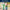 LEGO Daisies bouquet in a clear vase on a table with a lego cactus on the right and a dark blue text banner above saying display alongside other botanical sets, sold seperately.