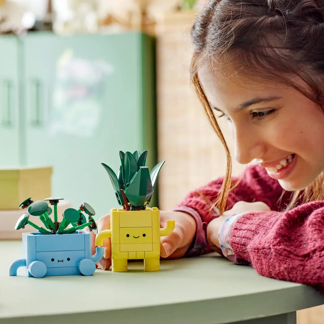 Lego Happy Plants set shown on a desk with a girl on the right shown playing with them.